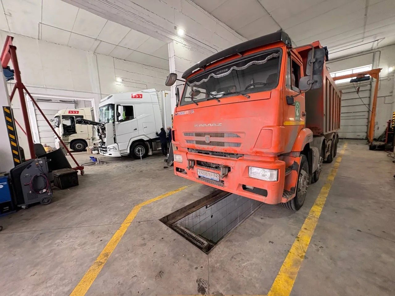 Оранжевый самосвал KAMAZ в ремонтном боксе «Э-Сервис»